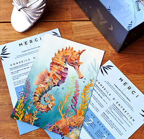 Thank you card featuring a colourful seahorse surrounded by vibrant seaweed, placed on a wooden table with pink heels and their shoebox