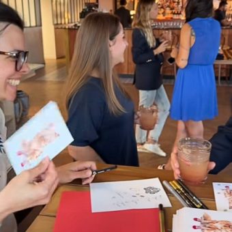 Julie Vigneron réalisant personnalisant une carte avec une de ses illustrations pour une cliente VIP lors d'un événement Minuit sur Terre